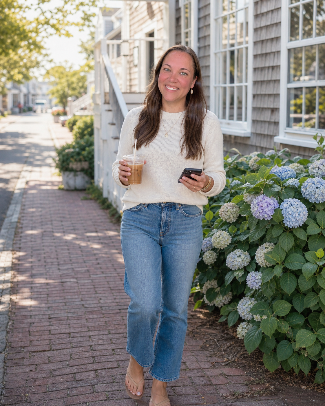 Maggie Rae walking with an iced coffee and her phone